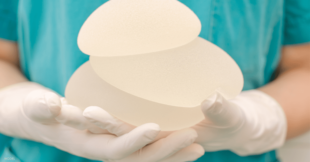 Gloved hands holding stack of textured breast implants
