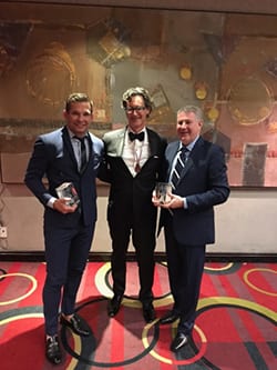 Dr. Calobrace holding award in suit with other award winners